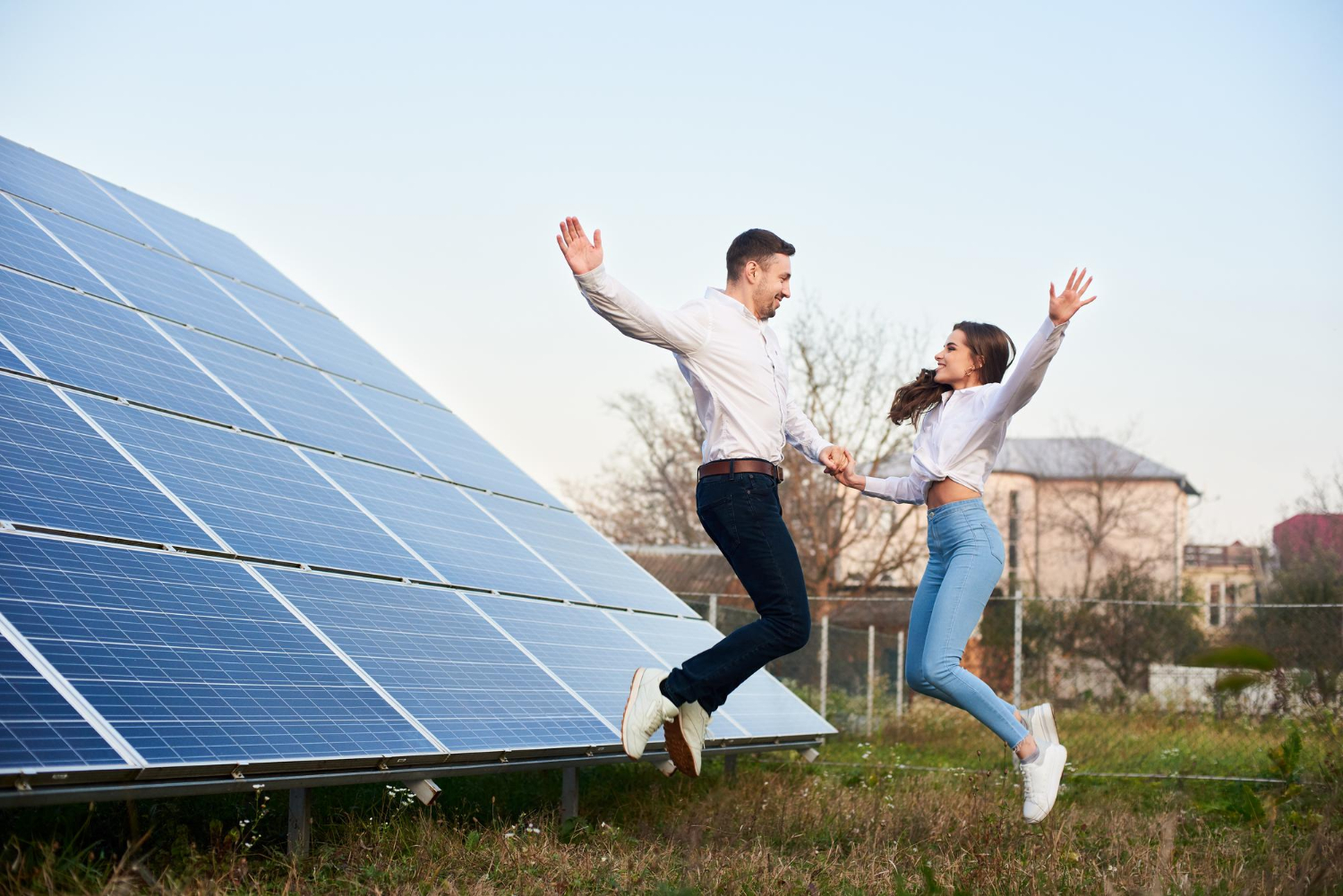young-family-jumping-holding-hands-near-house-with-solar-panels